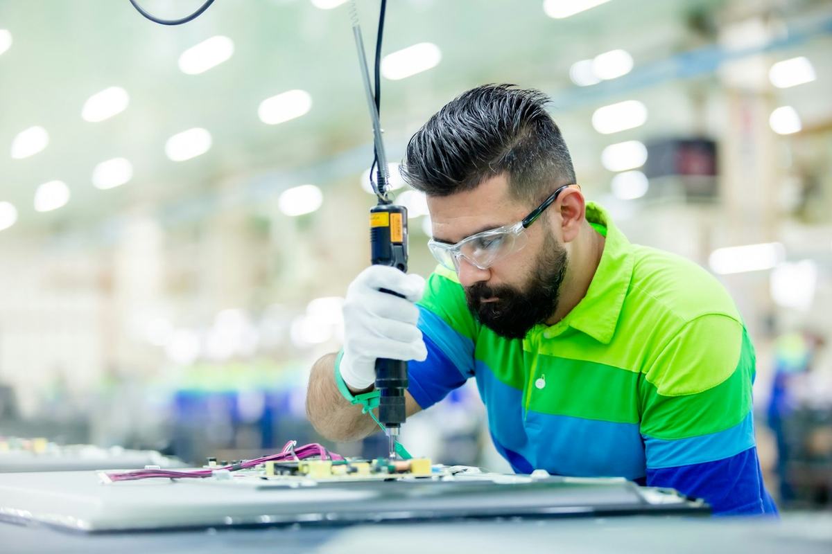 Technik montujący elektronikę w hali produkcyjnej